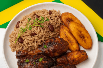 Jamaican flag and plate of Jamaican Food next to scotch bonnet peppers