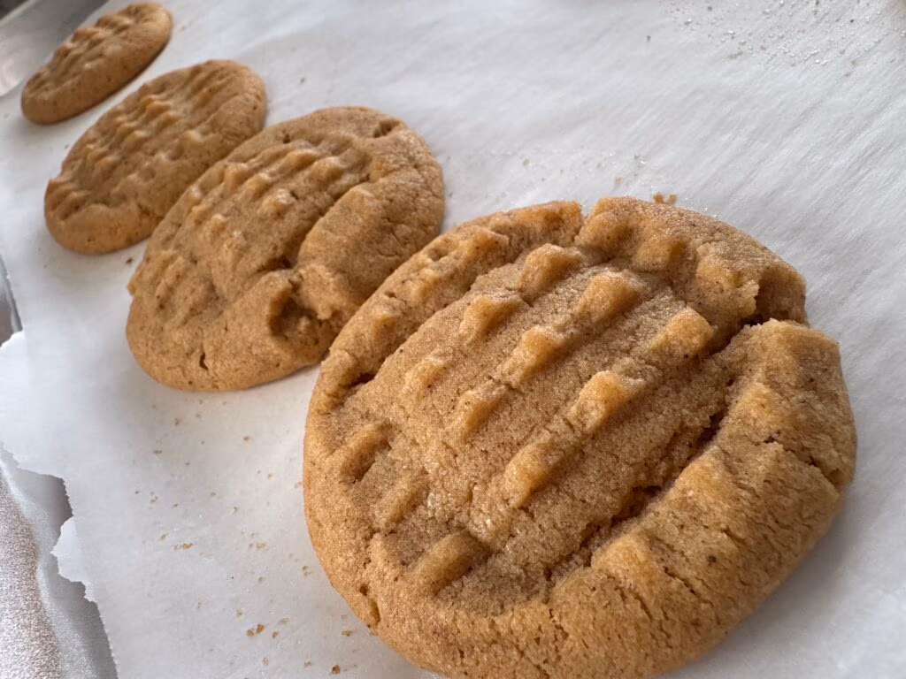 row of Peanut butter cookies, fresh out the oven on parchment paper