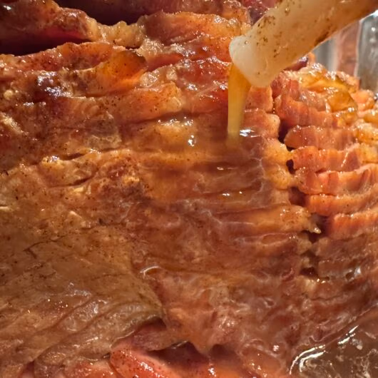 A holiday ham being glazed with brown sugar and pineapple