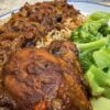 Jamaican brown stew chicken served with Jamaican rice and peas and steamed broccoli on a white plate