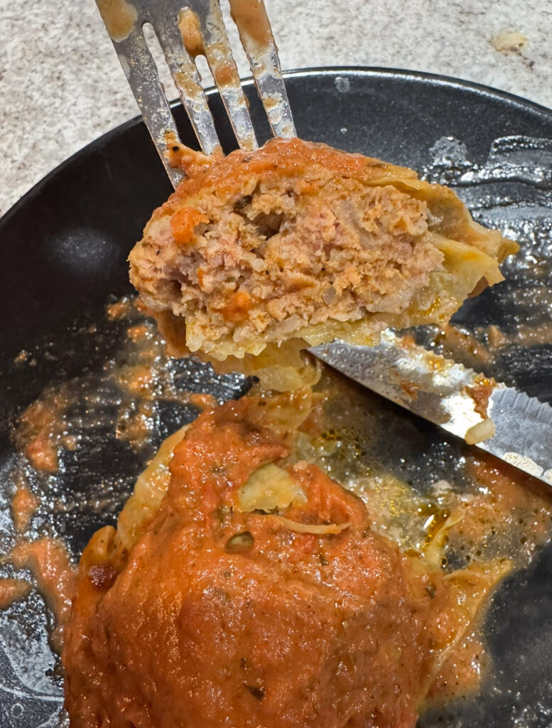 A bite of babbage roll showing the layer of meat and cabbage