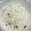 White Rice in a White bowl with pieces of cilantro and bits of lime zest