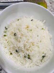 White Rice in a White bowl with pieces of cilantro and bits of lime zest
