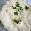 A close up of mashed potatoes topped with green onion