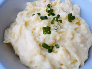 A close up of mashed potatoes topped with green onion