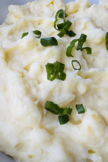 A close up of mashed potatoes topped with green onion