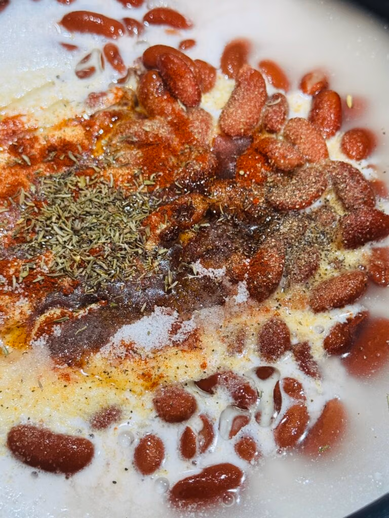 zoom in on jamaican rice and canned beans with coconut milk in pot with rice and water