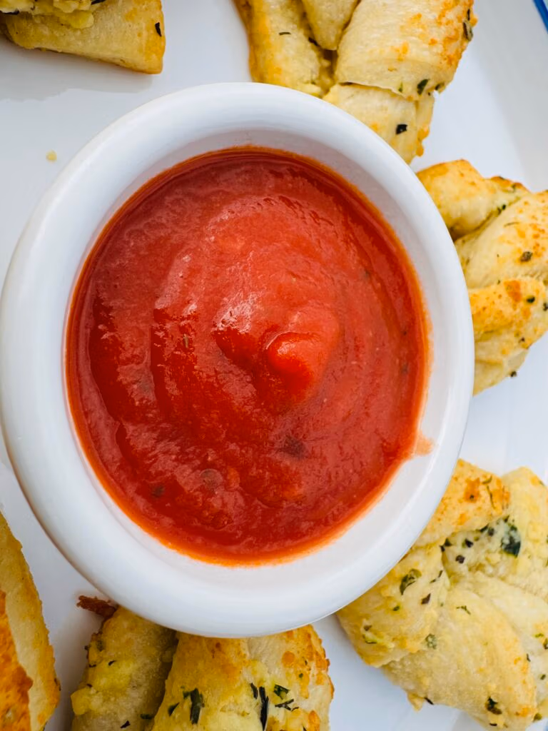 A white dipping bowl of marinara sauce