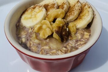 a red ramekin of banana bread overnight oats topped with bananas walnuts and cinnamon