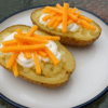 Baked Potatoes on a White plate topped with sour cream and cheese