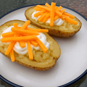 Baked Potatoes on a White plate topped with sour cream and cheese