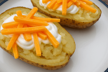 Baked Potatoes on a White plate topped with sour cream and cheese