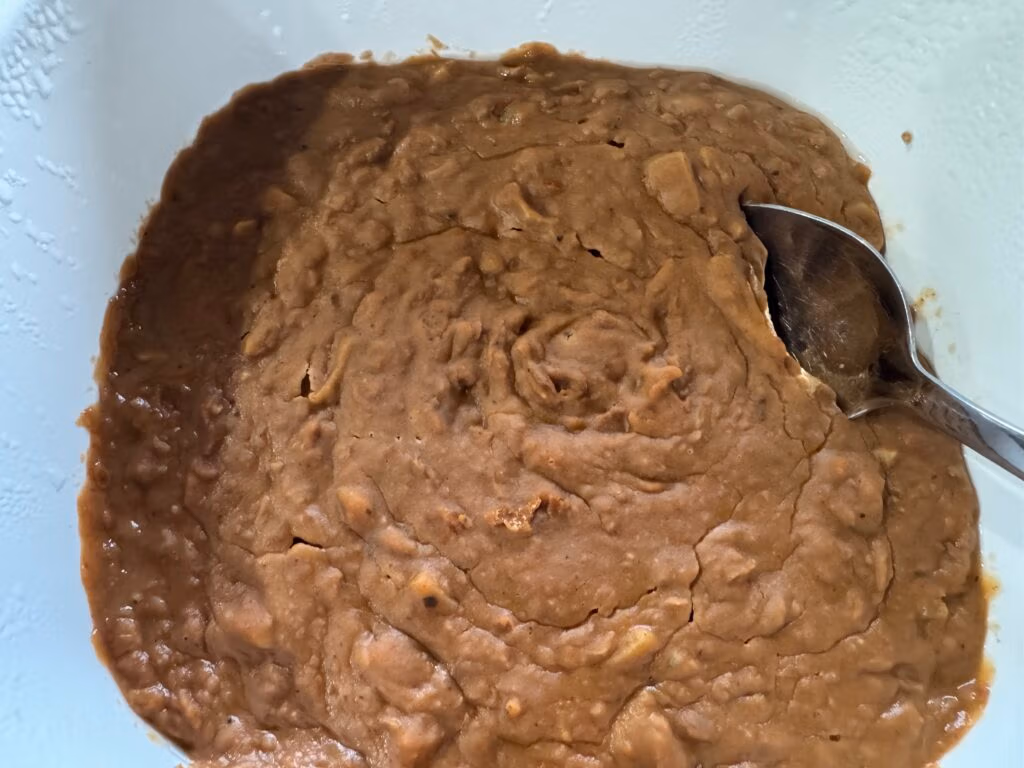 Refried Beans in a white serving dish with a silver spoon