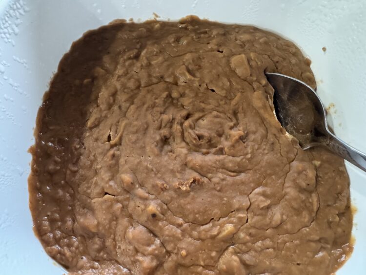 Refried Beans in a white serving dish with a silver spoon