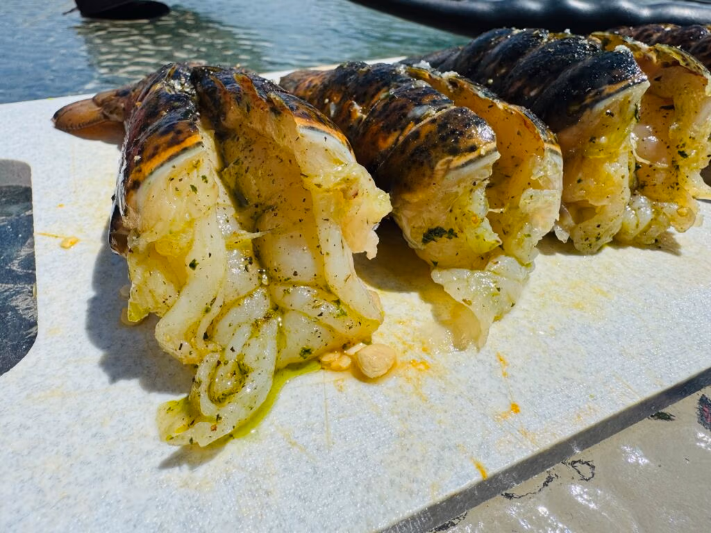 butter and herb basted Lobster tails ready to be grilled