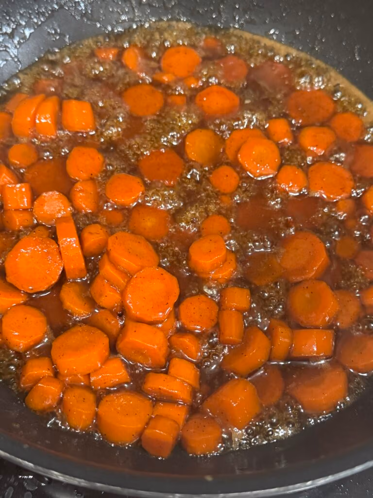 Candied carrots side dish slowly bubbling and cooking down to perfection
