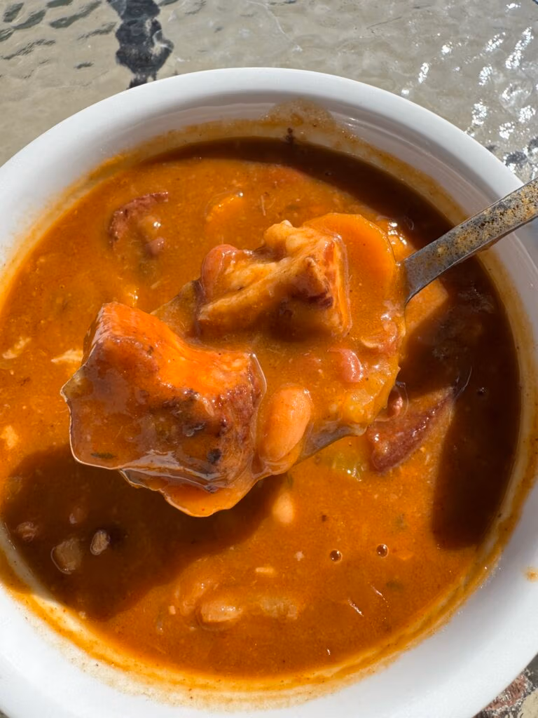 Close up of a spoonful of 15 bean ham soup in a white bowl