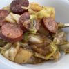 tender sauteed cabbage and smoked sausage in a white bowl