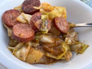 tender sauteed cabbage and smoked sausage in a white bowl