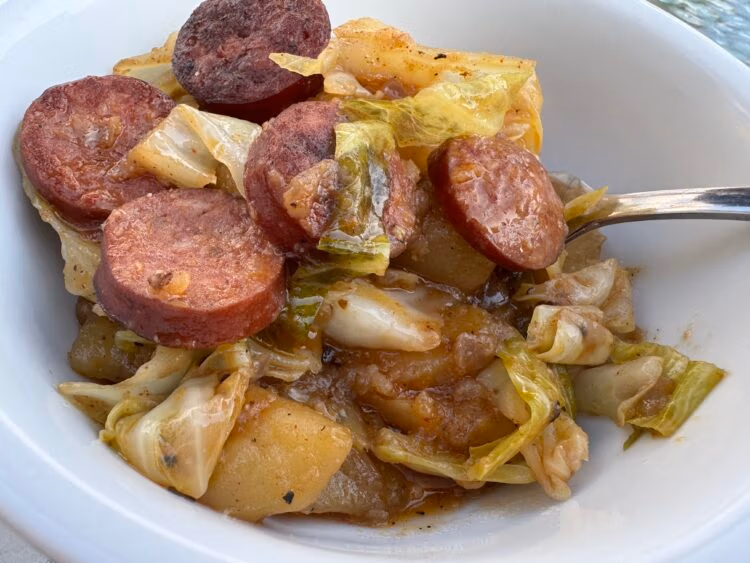 tender sauteed cabbage and smoked sausage in a white bowl