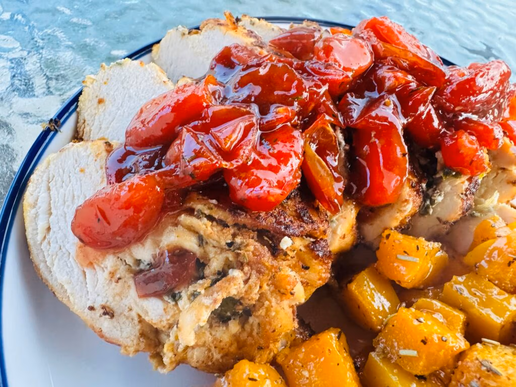 slices of goat cheese and spinach stuffed chicken breast with red wine and tomato topping