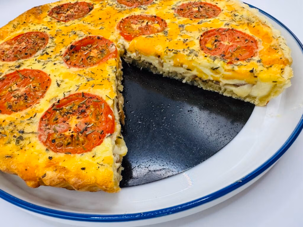 Tomato and Feta breakfast tart on a white plate with a slice missing