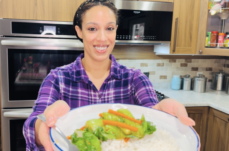 Camille of Camilles Comforting Cuisine holding a plate sauteed bok choy with white rice.